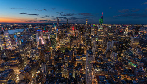 Aerial view of illuminated cityscape against sky during sunset