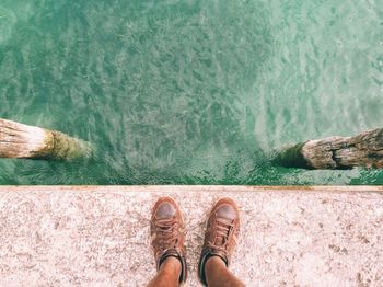 Low section of man standing on jetty over sea