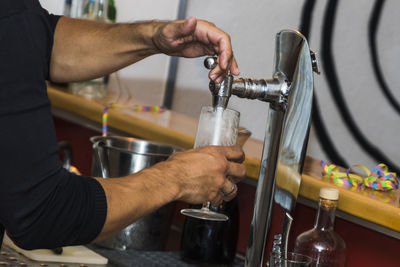 Midsection of man filling drink in glass