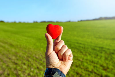 Midsection of person holding heart shape on field