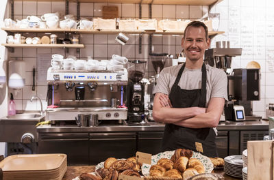 Portrait of salesman standing against kitchen counter at cafe