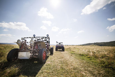 Off-road vehicle and quadbike on grassy field against sky