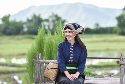 Woman in traditional clothing sitting against mountain