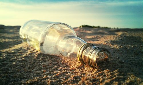 Close-up of glass bottle on sand at beach