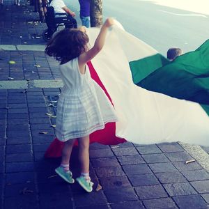 Rear view of girl standing on umbrella