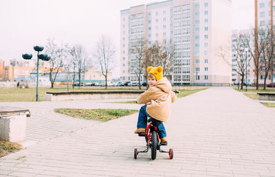 A small child learns to ride a bike for the first time in the city in spring