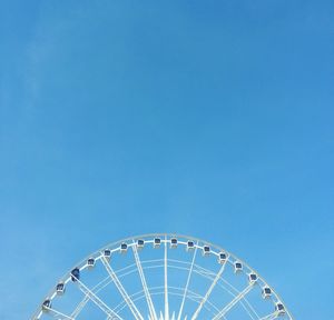 Low angle view of ferris wheel against clear blue sky