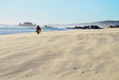 Man walking at beach against sky