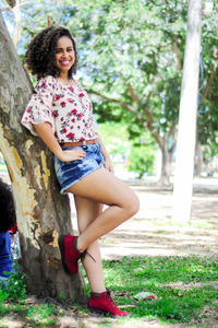 Portrait of smiling young woman sitting on tree trunk