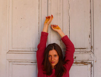 Portrait of young woman holding fruits against wall