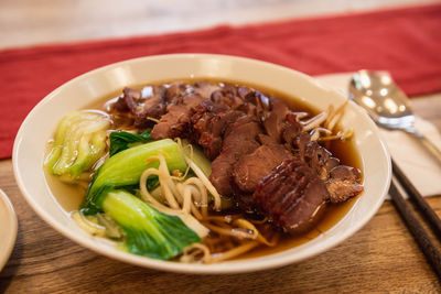 A bowl of soup noodles, topping with char siu and pak choi