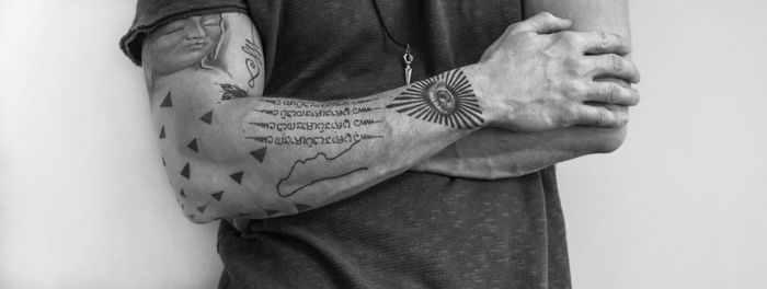 Midsection of man with tattoo standing against white background