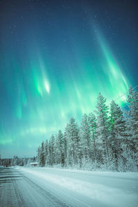 Scenic view of snow covered land against sky during aurora borealis