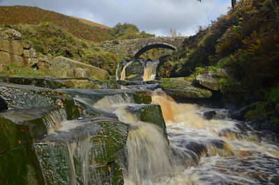 Water flowing through arch bridge over river