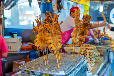 Close-up of fried squids on skewers for sale in market