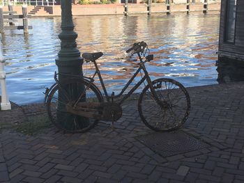 Bicycle parked on footpath by canal in city