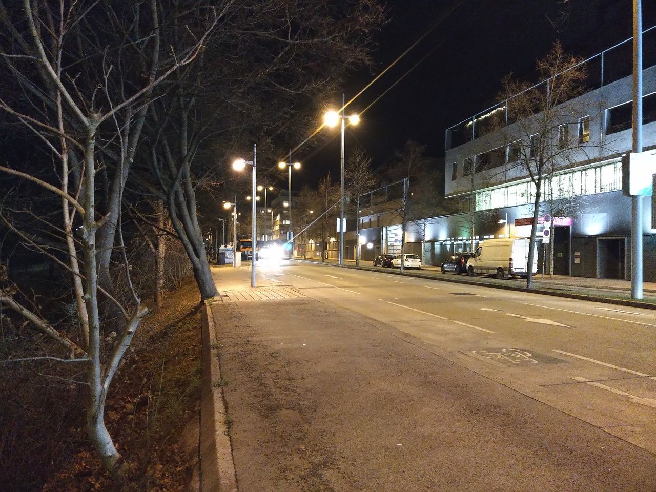 EMPTY ROAD BY ILLUMINATED STREET LIGHT AT NIGHT