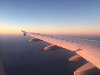 Close-up of airplane wing against sky during sunset