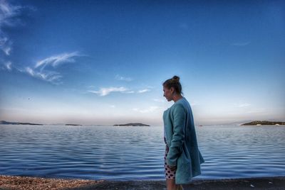 Side view of man looking at sea against blue sky