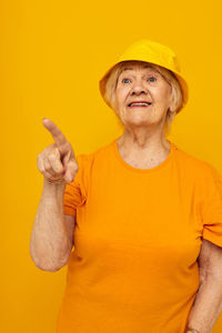 Portrait of woman gesturing against yellow background