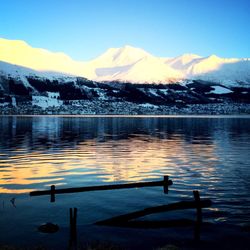 Scenic view of lake by snowcapped mountains against sky