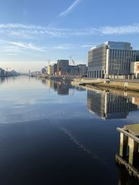 Buildings by river against sky