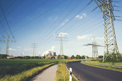 Electricity pylon by road against sky