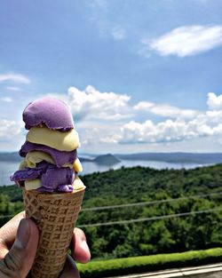 Close-up of hand holding ice cream against sky