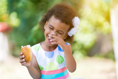 Smiling girl eating food in park