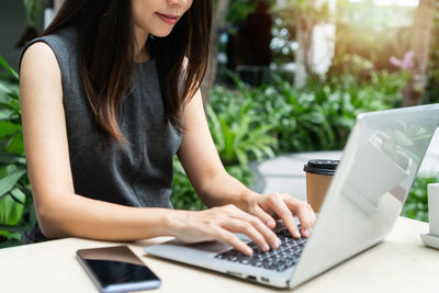 Midsection of woman using laptop on table