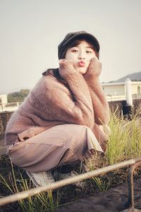 Portrait of young woman puckering lips while crouching by plants