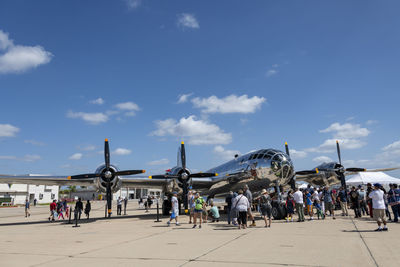 Group of people on airport runway against sky