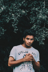 Portrait of young man standing against trees