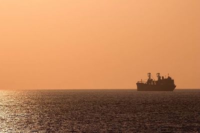 Boat sailing in sea at sunset