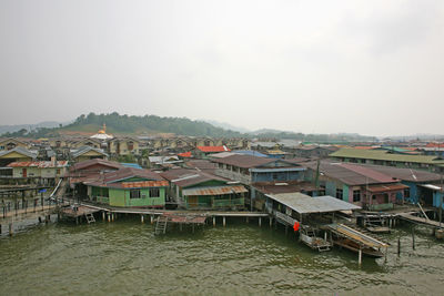 Houses by river against clear sky