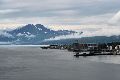 Scenic view of sea by snowcapped mountains against sky