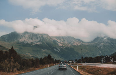 Cars on road by mountains against sky