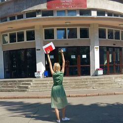 Full length of woman holding umbrella against building in city