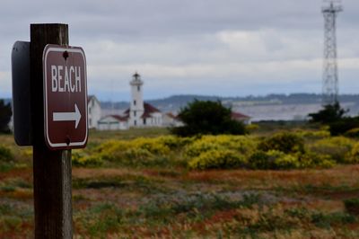 Close-up of road sign on field against sky