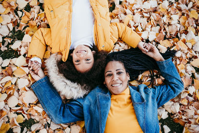Portrait of happy young woman lying on leaves during autumn