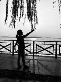 Side view of silhouette woman standing on footpath against sea