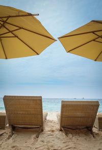 Chairs on beach against sky