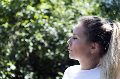 Close-up of young woman against trees