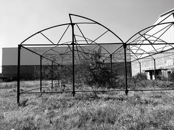 Abandoned greenhouse in field against sky