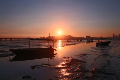 Boats moored at beach against sky during sunset