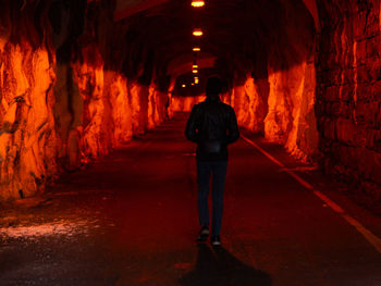 Rear view of man standing in illuminated tunnel