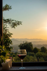 Wine glass on table against sky during sunset