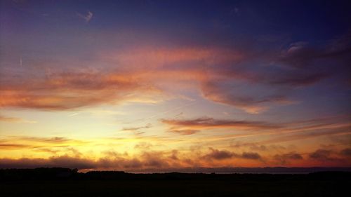 Scenic view of silhouette landscape against dramatic sky during sunset