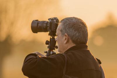 Mature man photographing with camera during sunset