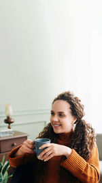 Portrait of young woman sitting on table against white background